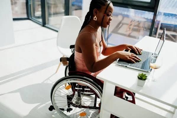 Femme en fauteuil roulant travaillant sur un ordinateur portable