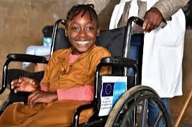 Jeune fille souriante assise dans un fauteuil roulant